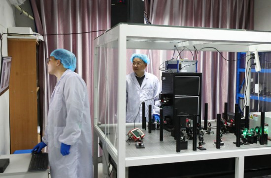 阮昊研究員（右）和趙苗博士（左）在上海光機所光學實驗室，利用國際首創的雙光束調控聚集誘導發光超分辨光存儲技術做寫入試驗（2月29日攝）。