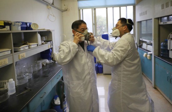 趙苗博士（右）在上海光機所材料實驗室內協助阮昊研究員佩戴防護口罩（2月29日攝）。